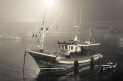 barco de pesca en el puerto comillas con niebla